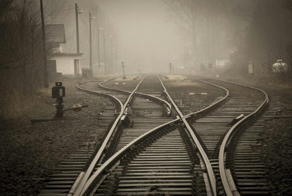 A foggy railway junction symbolizing decision-making and navigating complex choices, representing the crossroads consultants face when balancing strategy and PowerPoint design tasks.